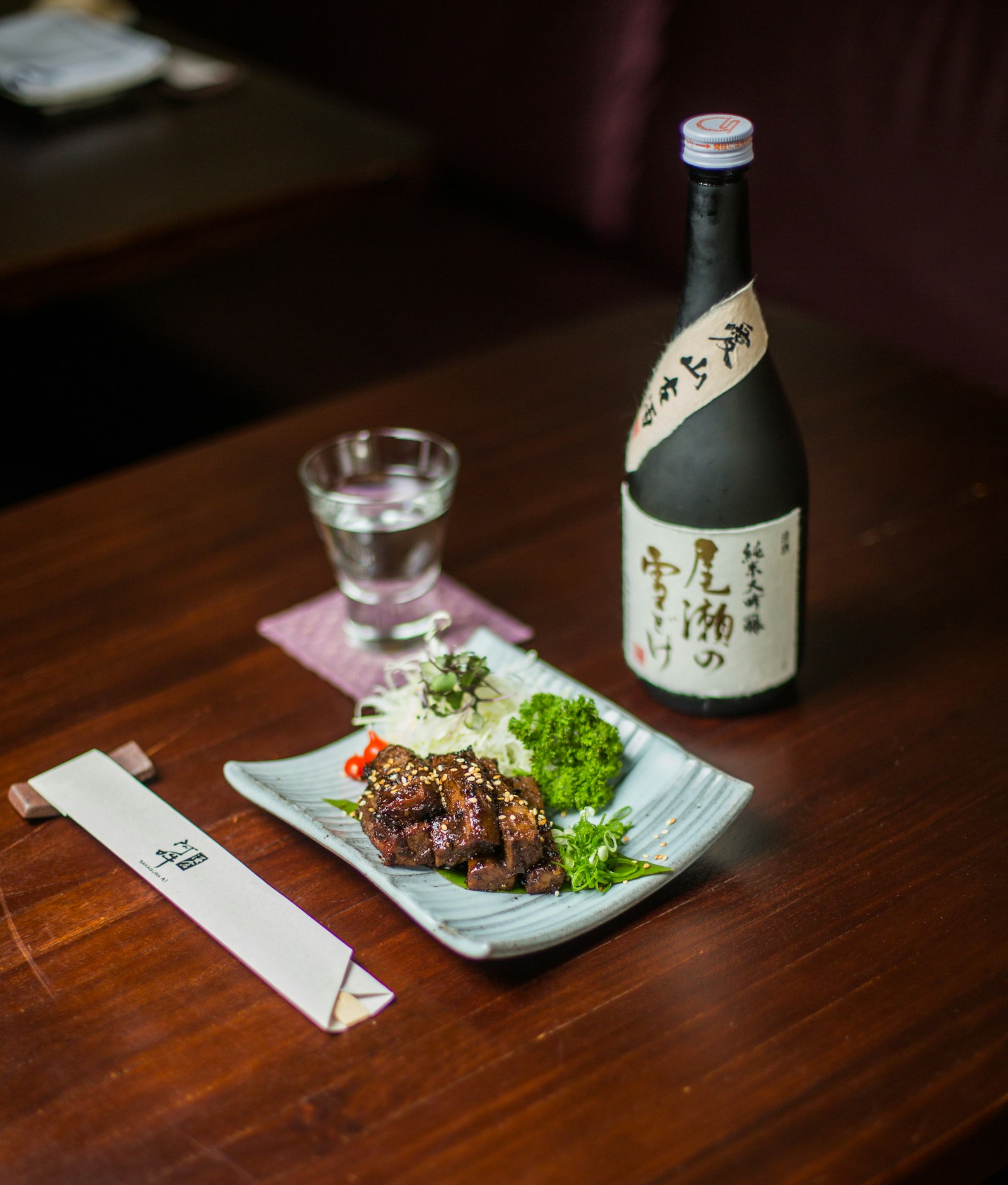 Bottle of sake with a small cup and a plate at Kaen Ramen
